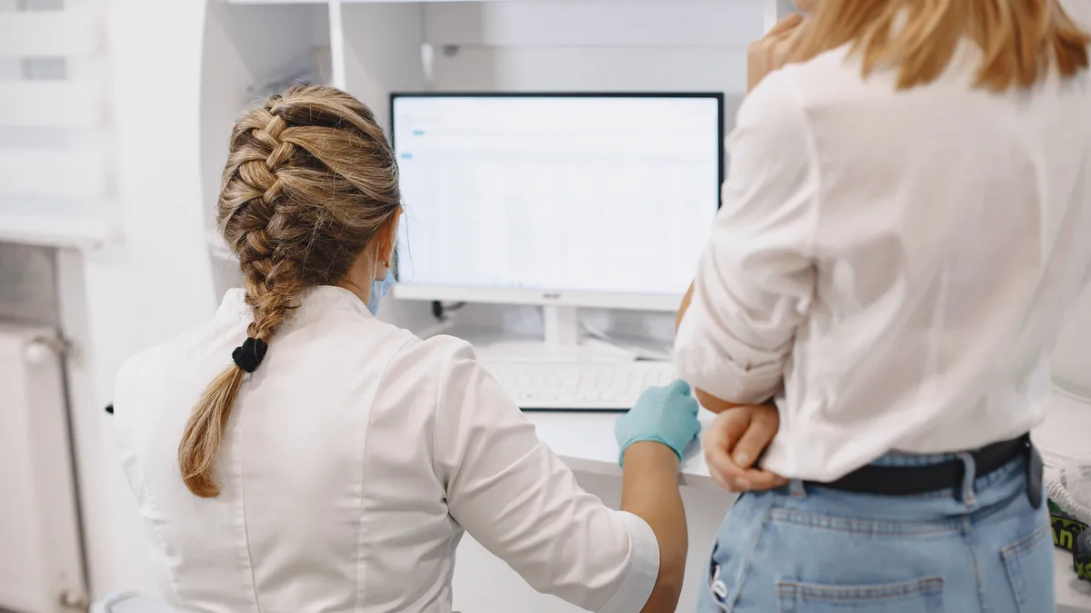 Two healthcare workers review data on a computer screen, the kind of safety information a Patient Safety Organization analyzes